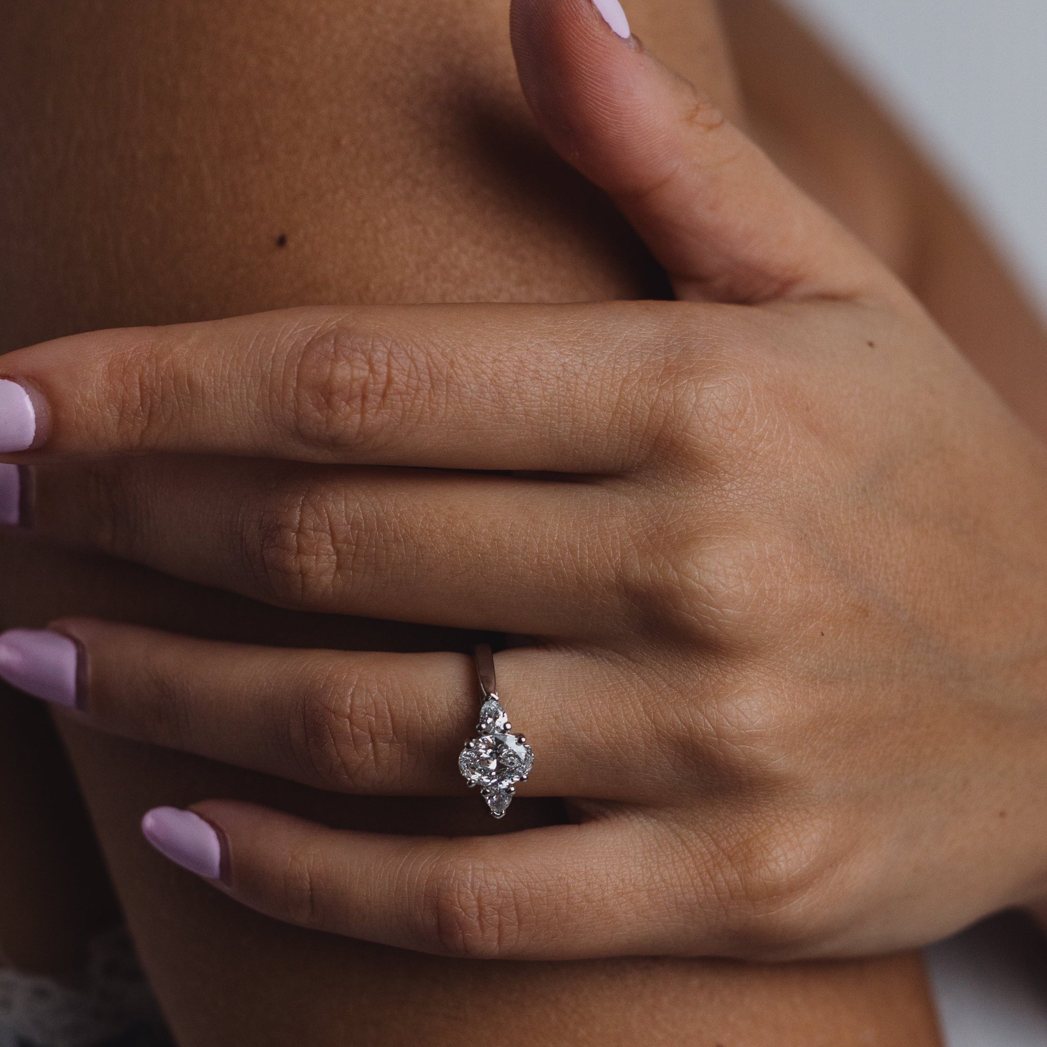 Hand wearing a diamond ring with a blurred background