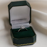 Diamond ring in a green jewelry box on a white fabric background