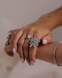 Close-up of a hand wearing multiple silver rings with a blurred background