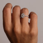 Diamond ring on a person's finger against a neutral background