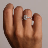 Diamond ring on a person's finger against a neutral background