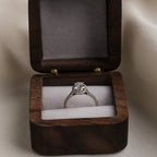 Wooden ring box with a diamond ring inside on a neutral background