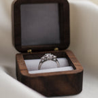 Trilogy diamond ring in a wooden box on a light background