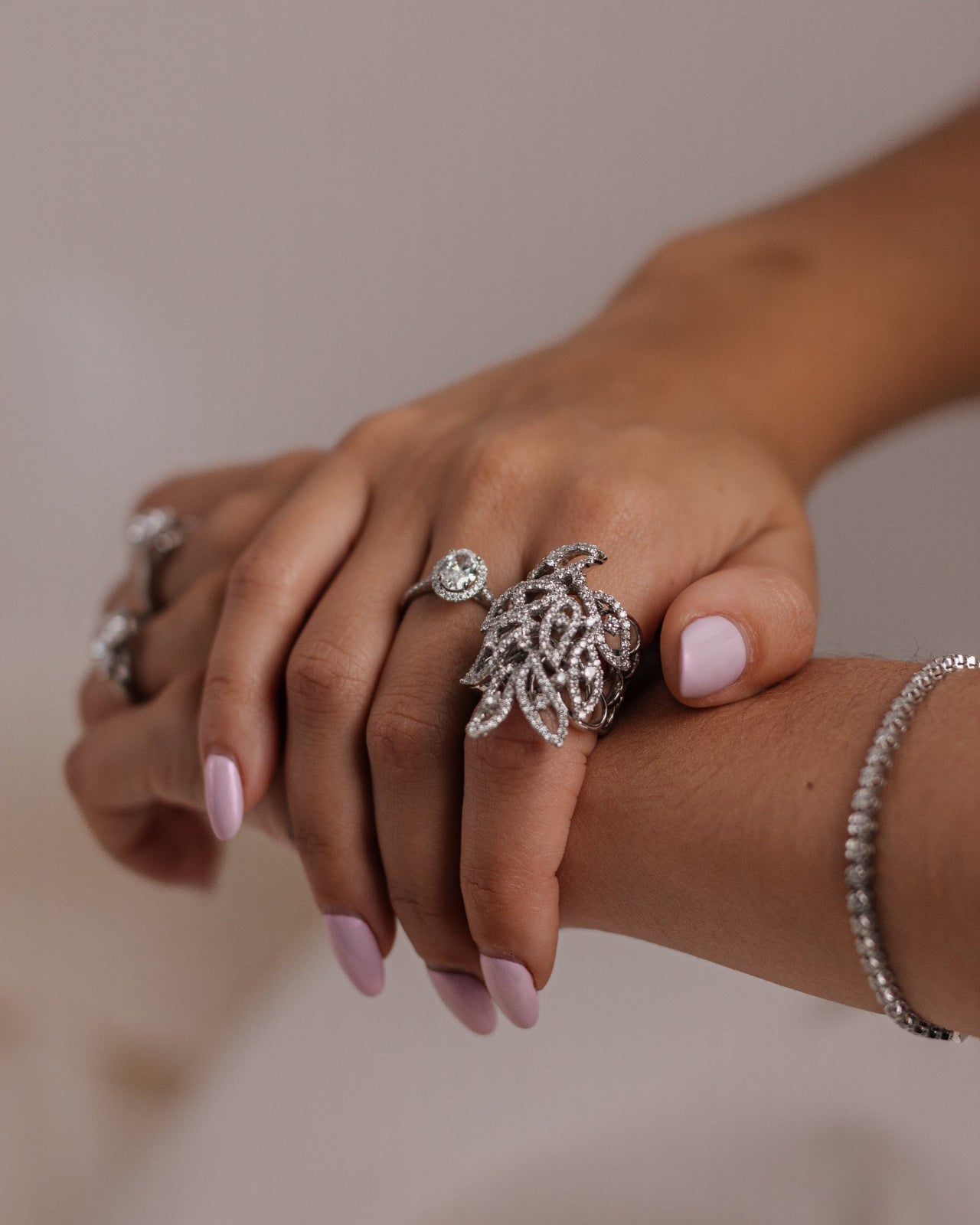 Close-up of a hand wearing multiple silver rings with a blurred background