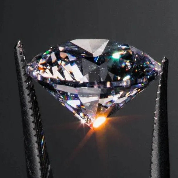 Close-up of a diamond held between tweezers against a dark background